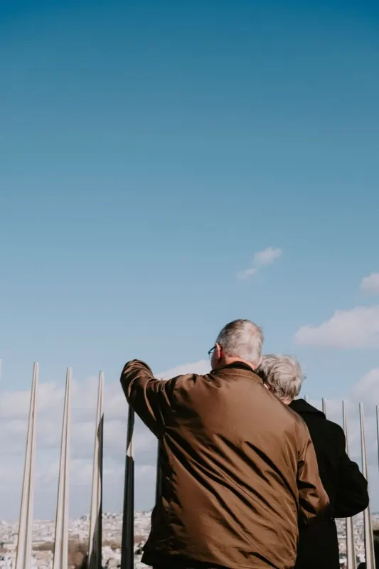 Casal apontando para a vista de uma cidade durante uma viagem